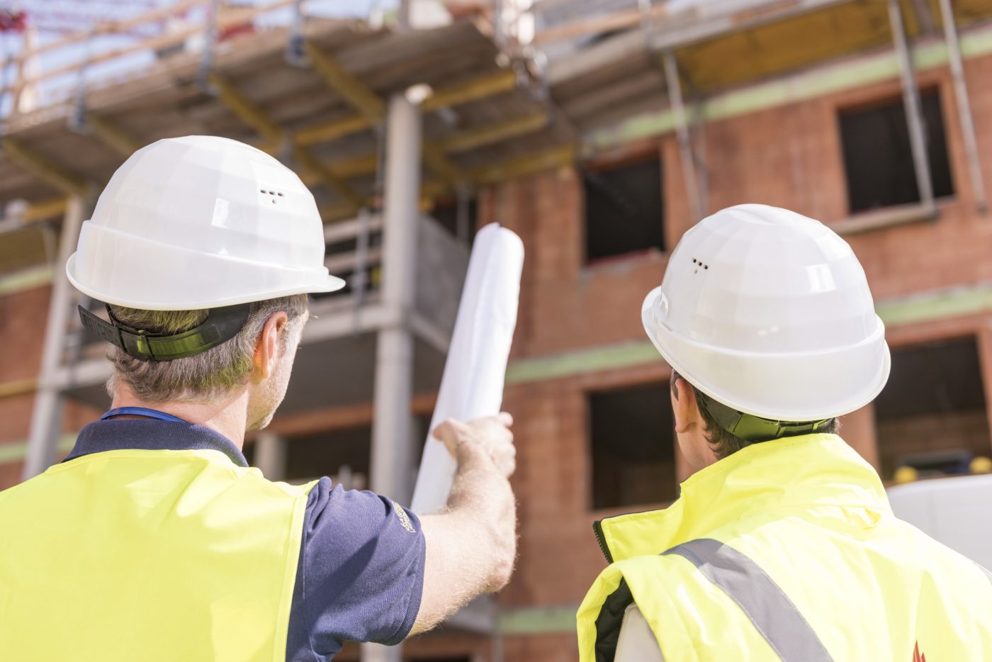 Builder pointing at building shell with blueprint