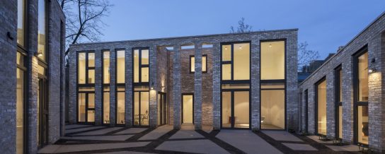 Modern brick building with large glass windows at night