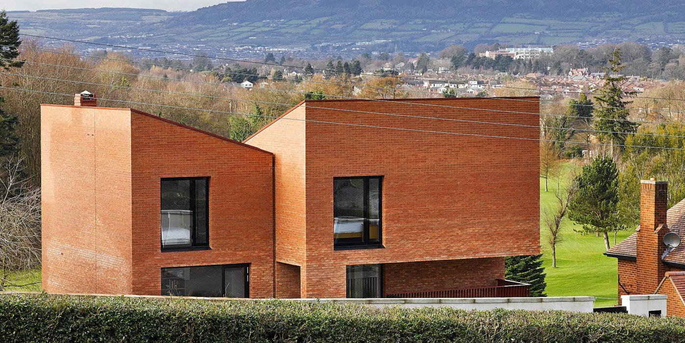 Asymmetrical brick house with hills in the background