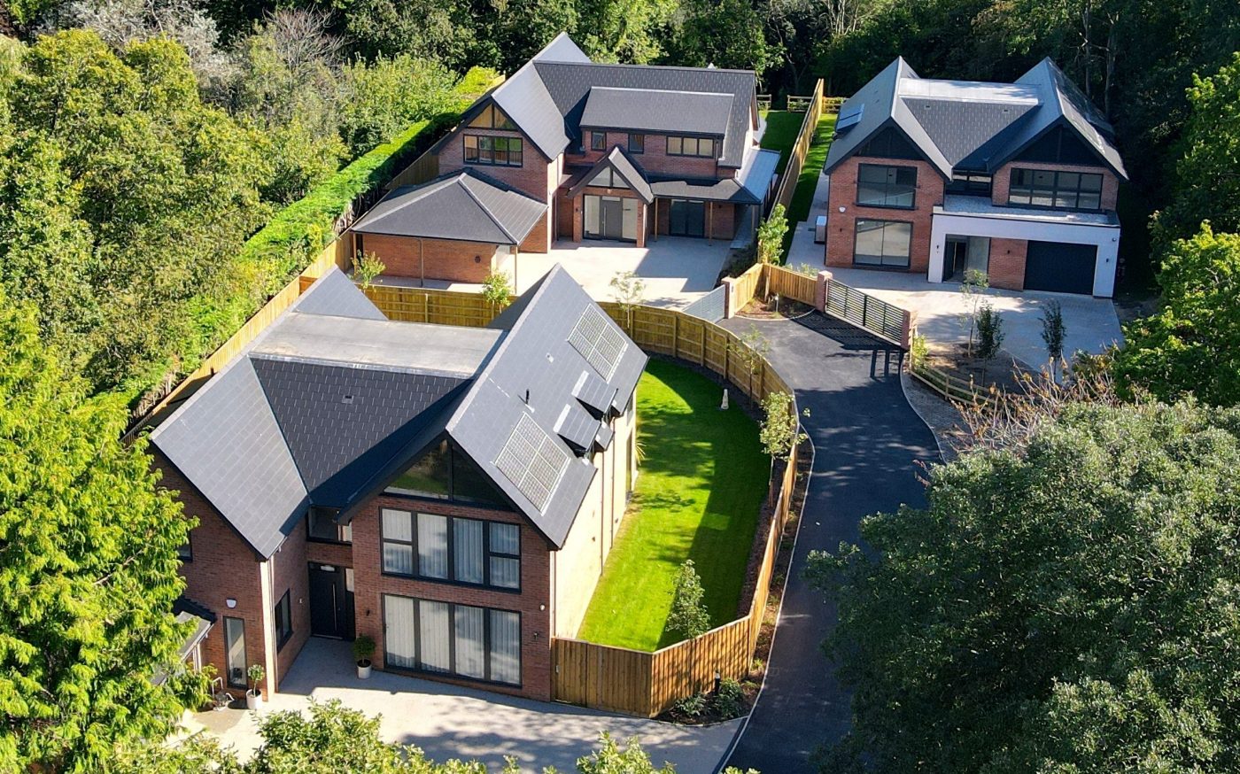 Three luxury new detached homes surrounded by trees and greenery