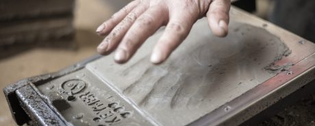 Man emprinting hand on clay tile