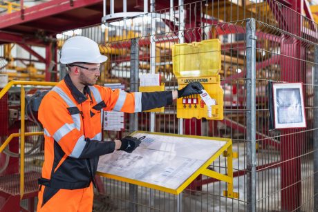 Factory worker locking out machine with LOTOTO safety hasp