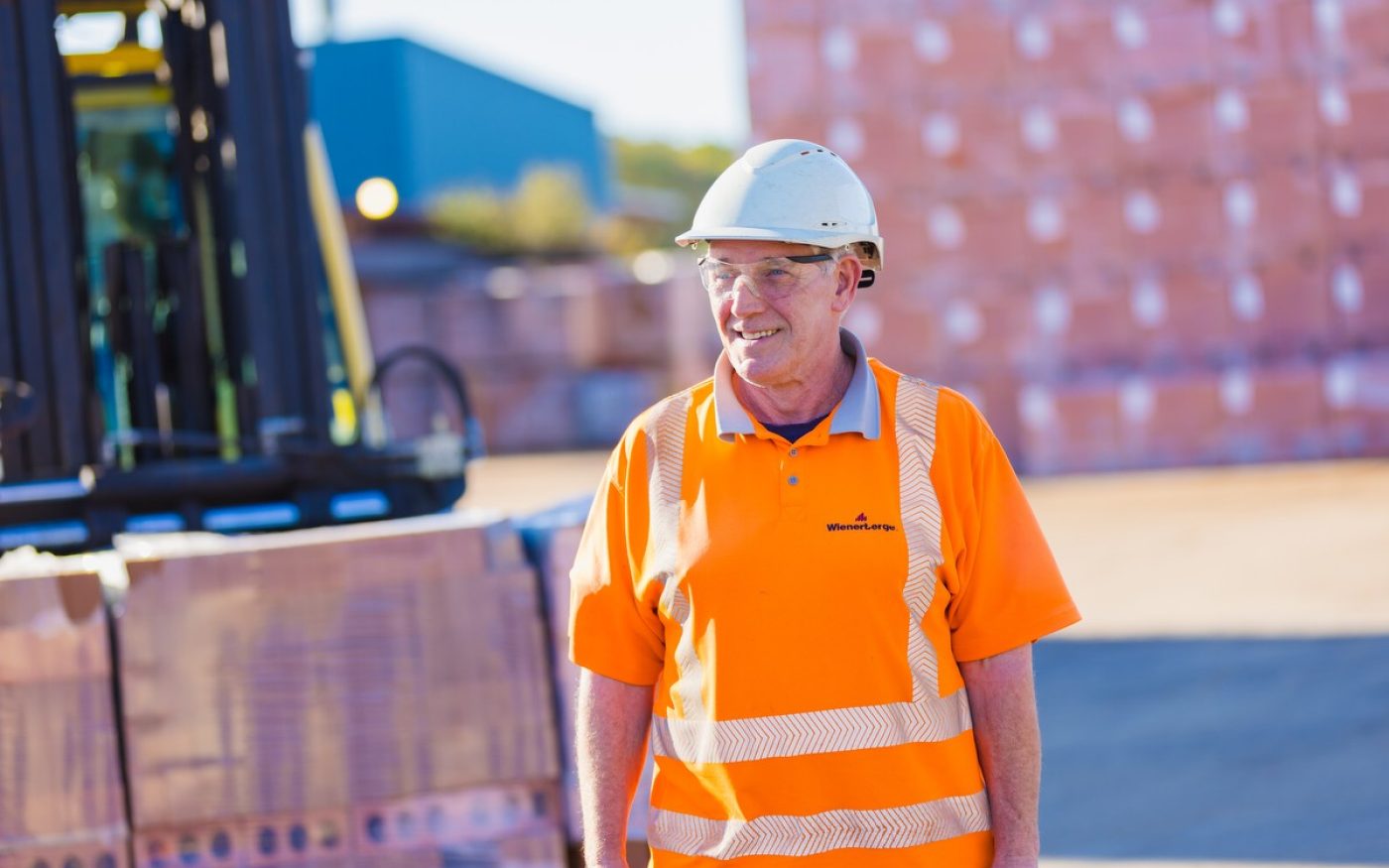 Man in protective equipment overseeing brick transport