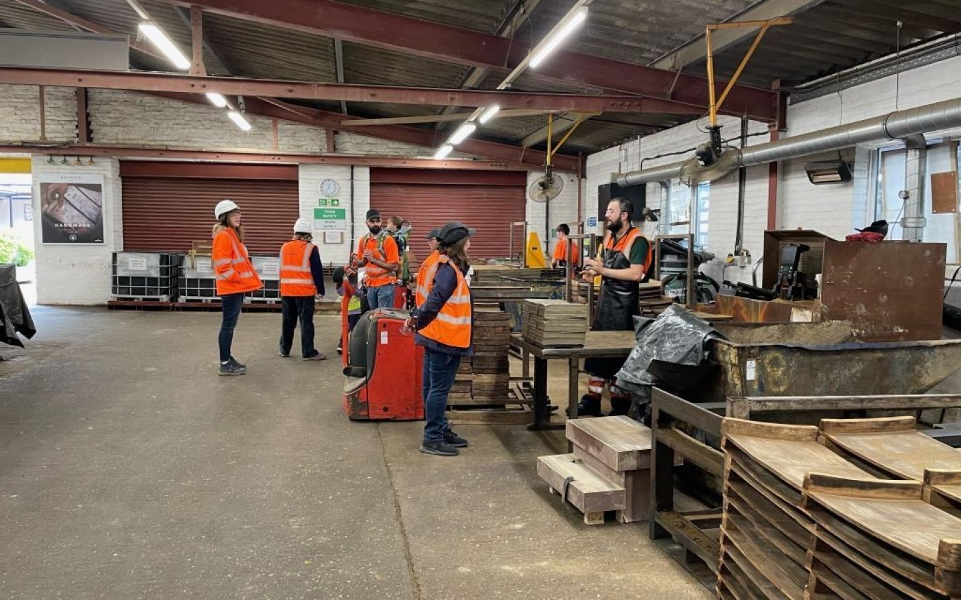 Visitors in hi-vis jackets watchomg live demonstrations of making tiles