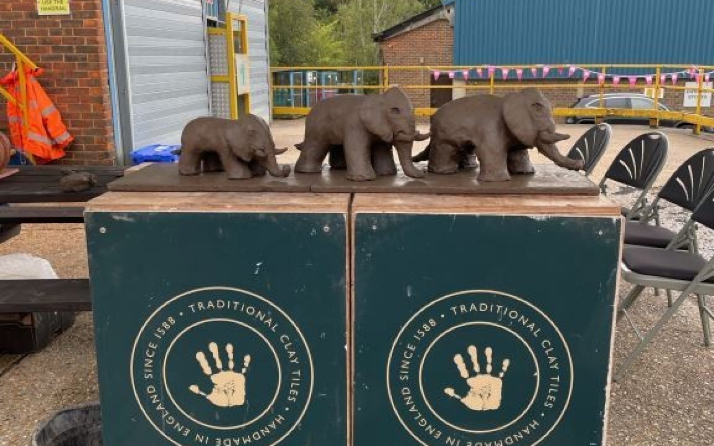 Three hand made clay elephants lined up on a Keymer stand