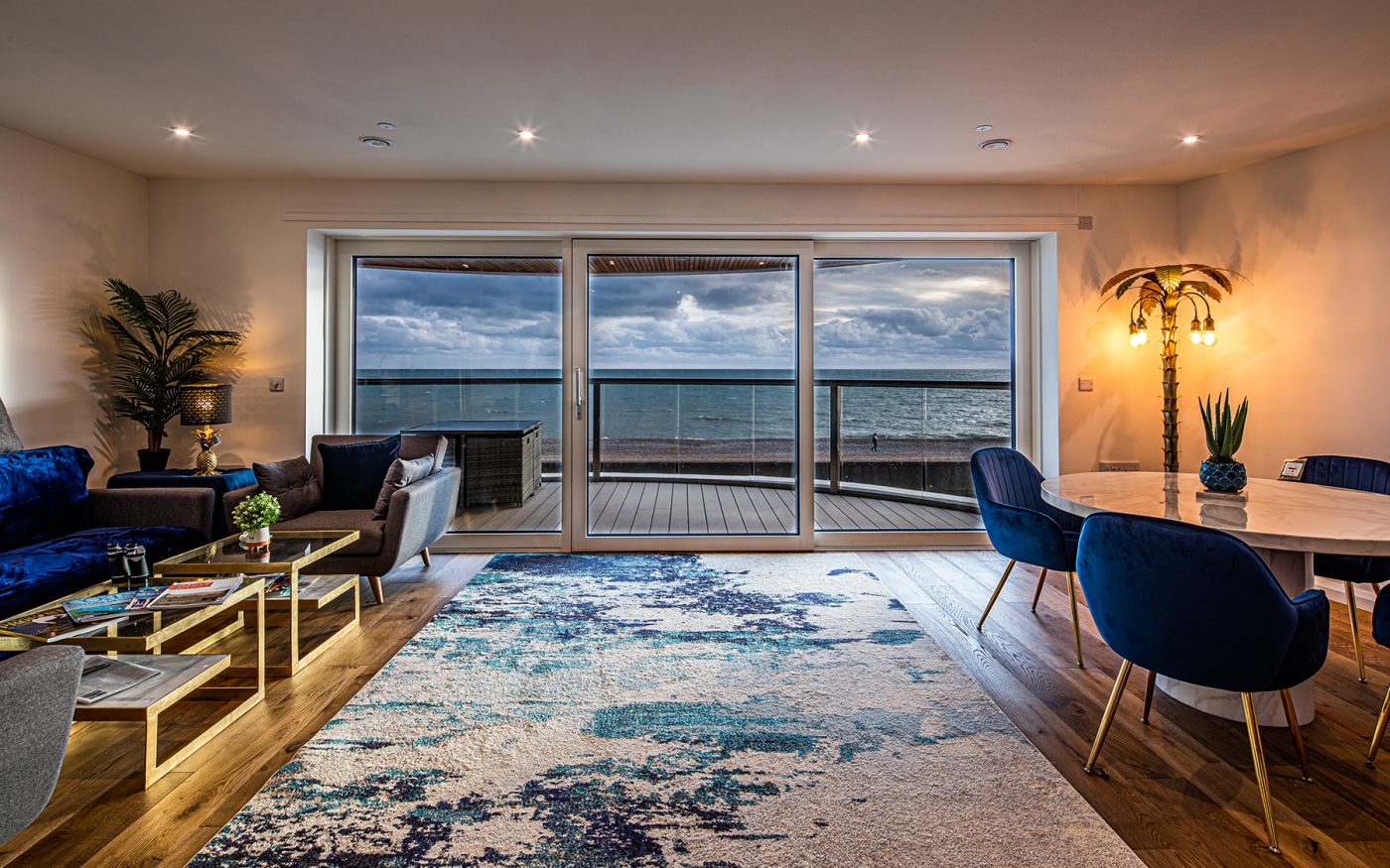 Modern living room interior with large patio window overlooking balcony and sea view