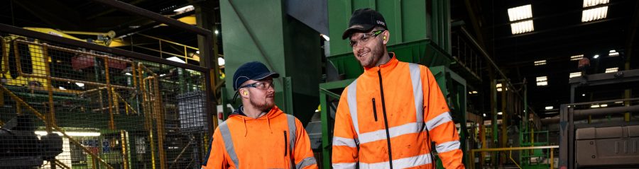 2 engineering apprentices walking in the factory together smiling
