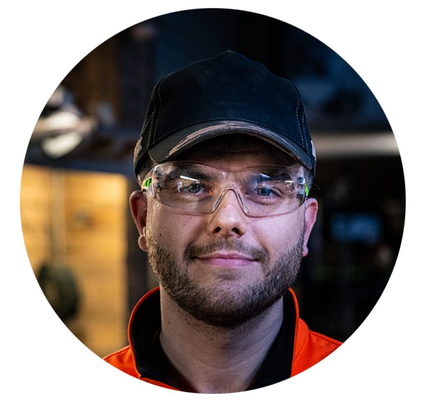 Corey Gilks smiling towards the camera wearing protective glasses and a cap