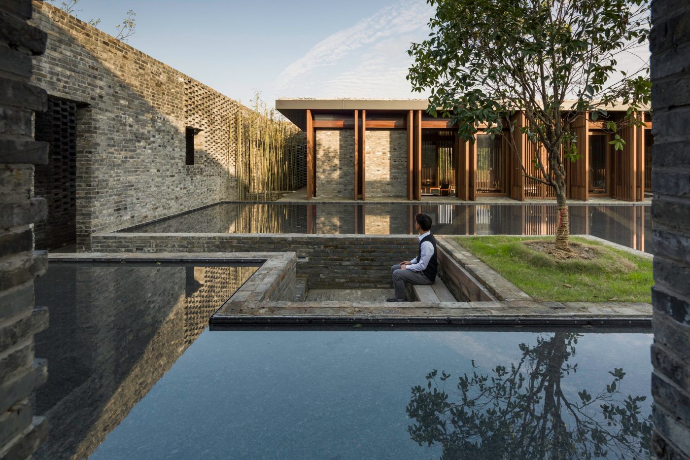 Boat on canal with modern brick apartment buildings, pedestrians walking
