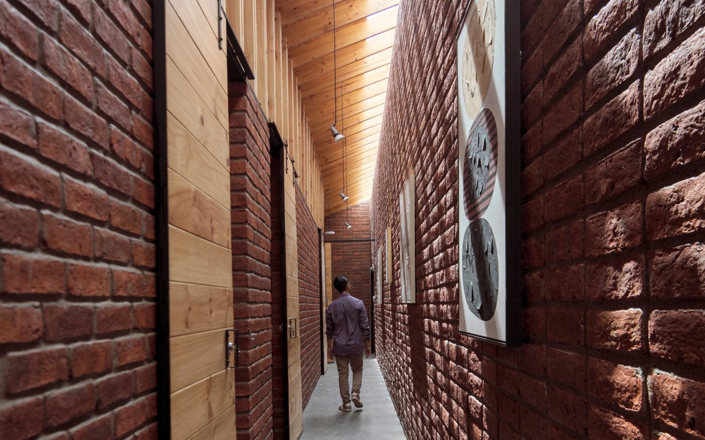 Man walking down brick wall corridor in the House that Inhabits