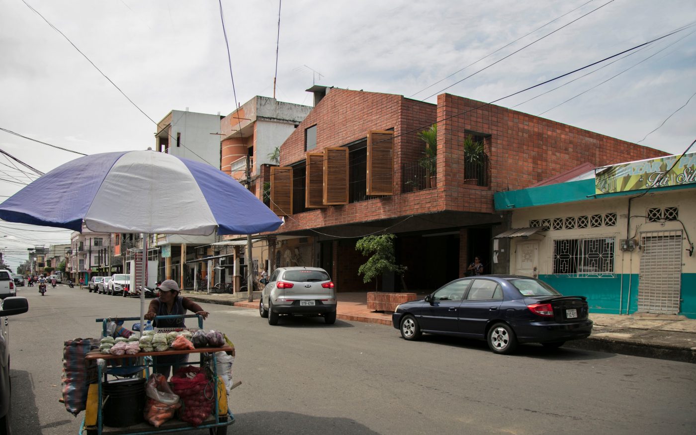 Fruit stall and cars on the street outside a modern brick building in Babahoyo city