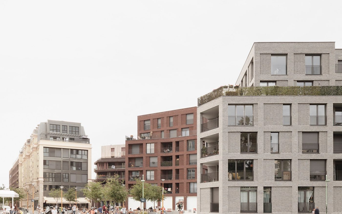Man sat by canal, watching boat on water, in front of modern brick apartment buildings
