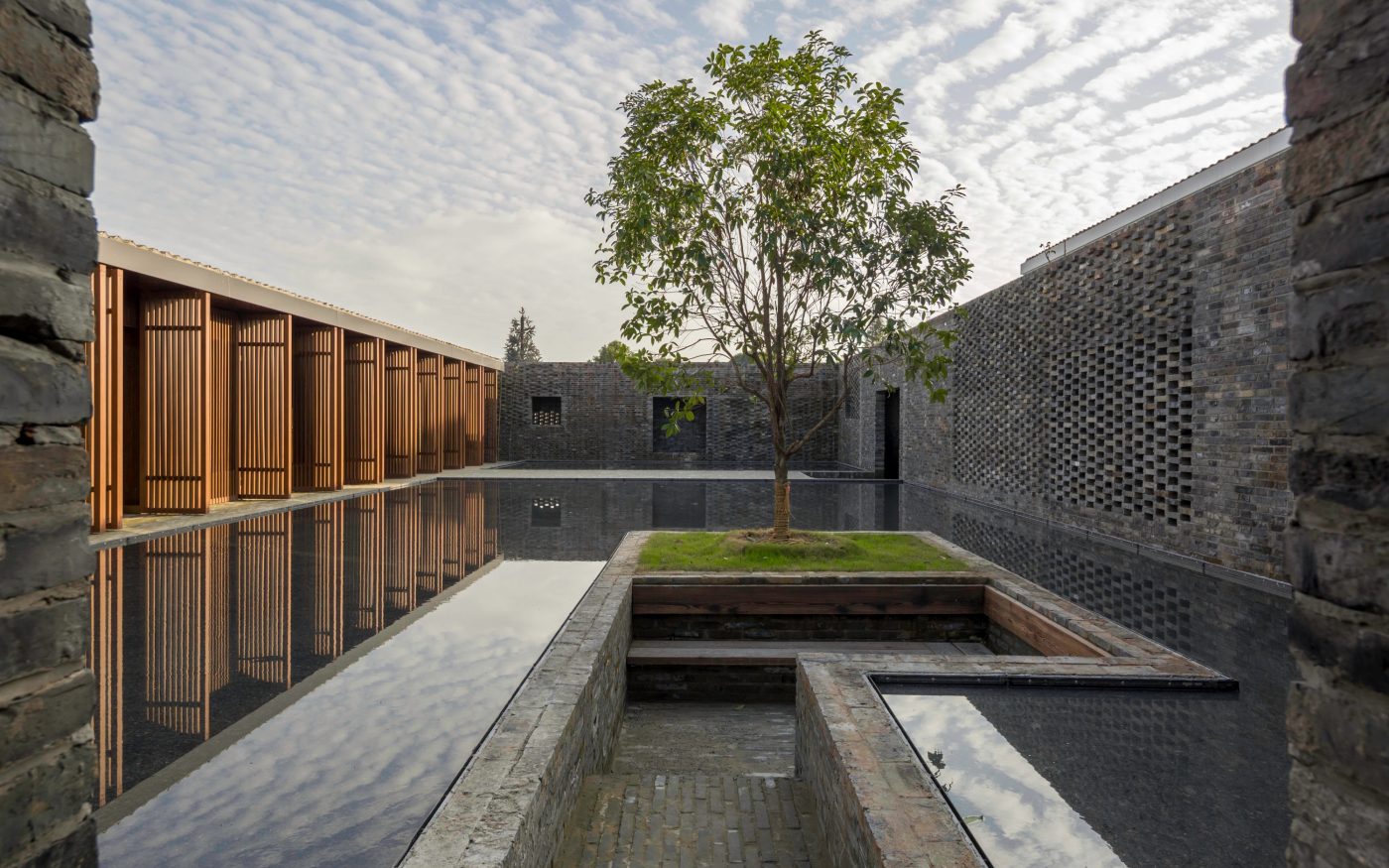 Tree in the centre of reflective pools in courtyard of modern Tsingpu Yangzhou Retreat hotel