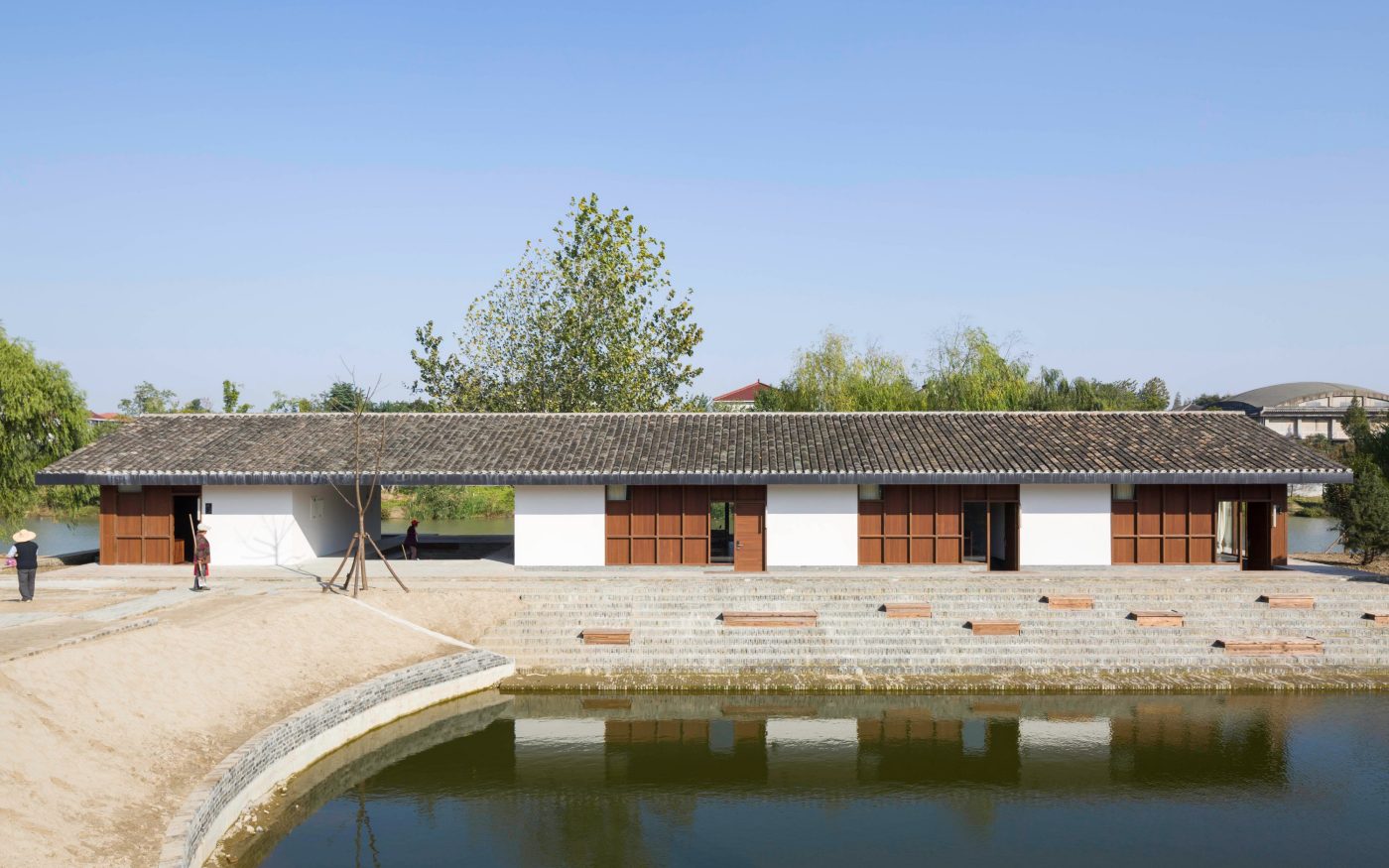 Modern luxury hotel single-storey building beside pool, with trees and blue sky