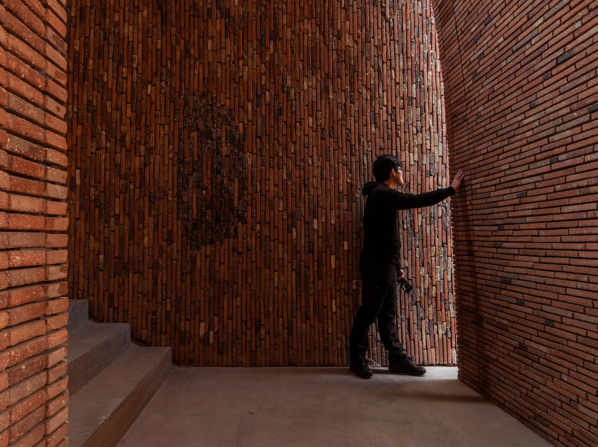Man looking through window slit in brick wall at foot of stairs
