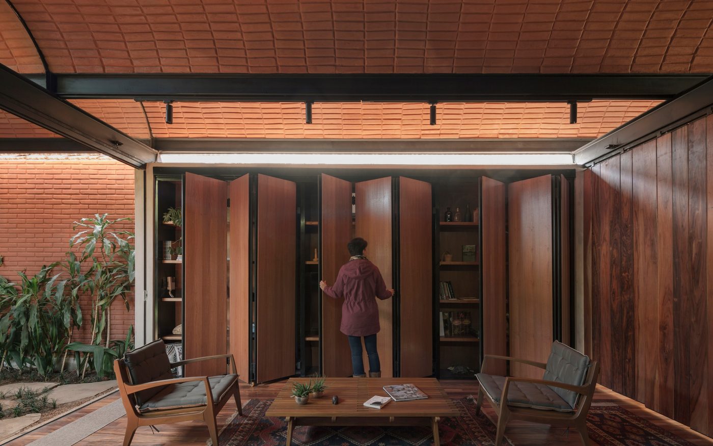 Woman opening cabinets in a modern living room with curved brick ceiling