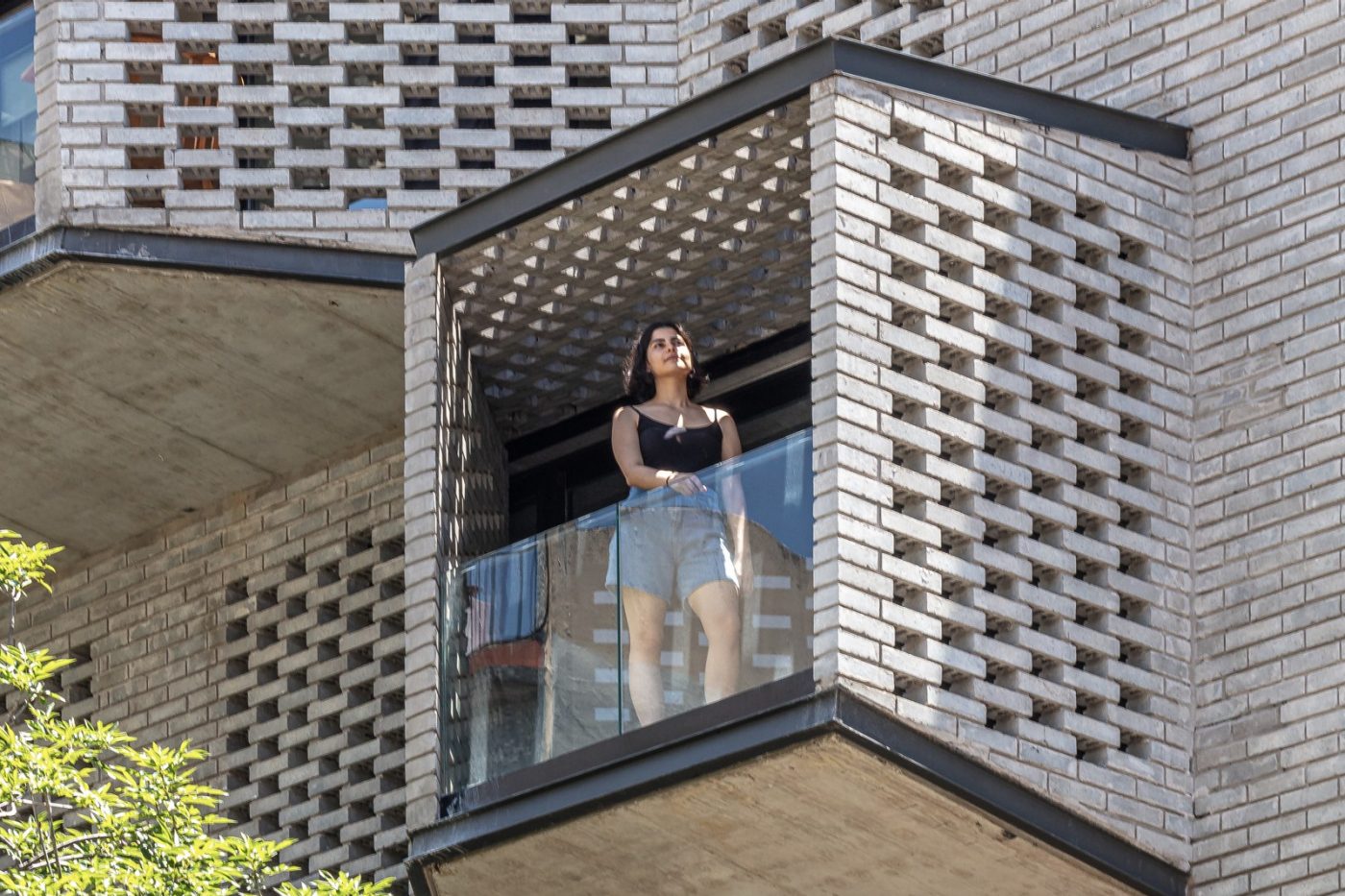 Woman standing on balcony with lattice grey brickwork