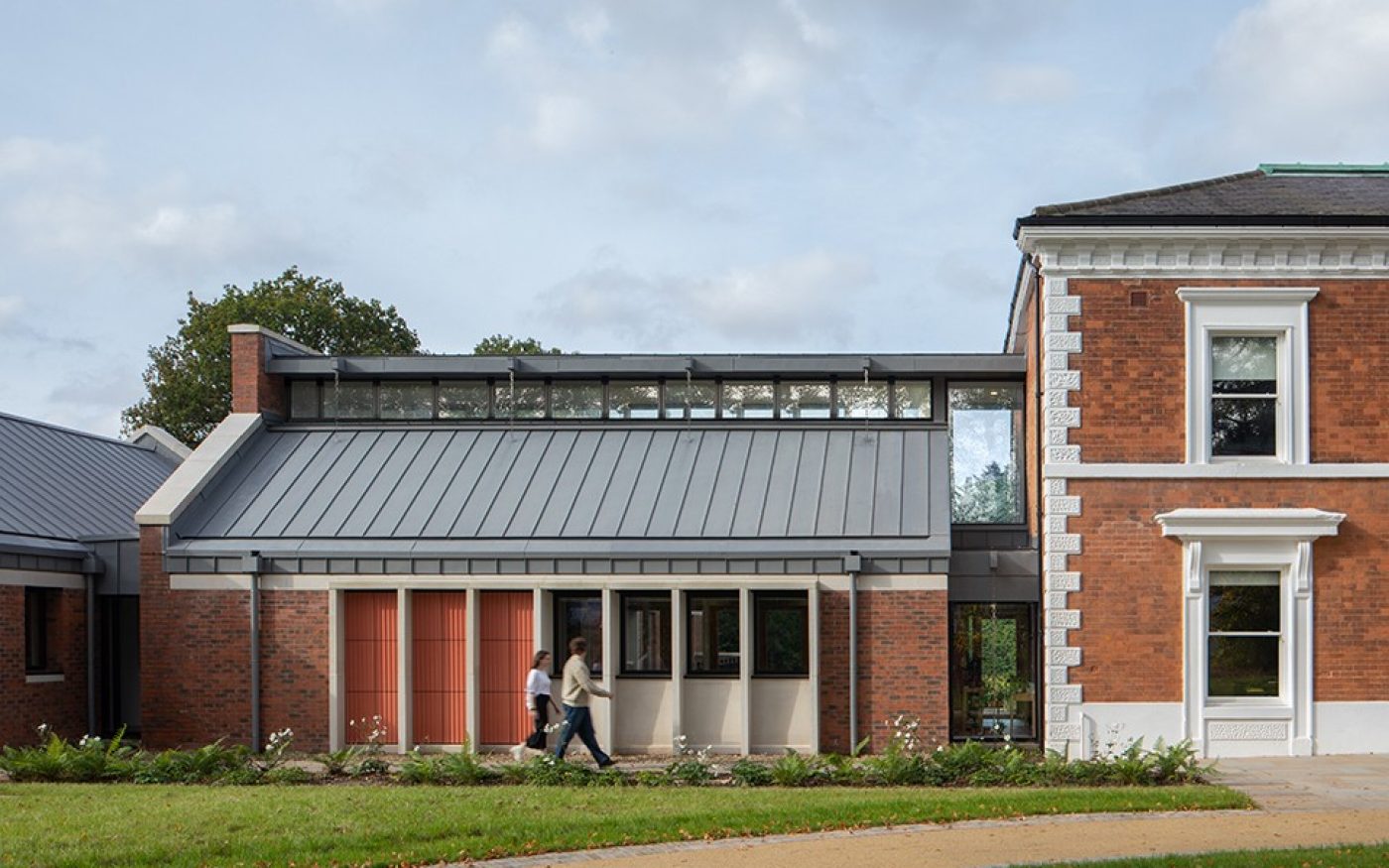 two people walking past the red brick development