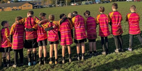 Group of under 9/10s in a line with their backs to the camera showing off wienerberger logo on the back of their shirt