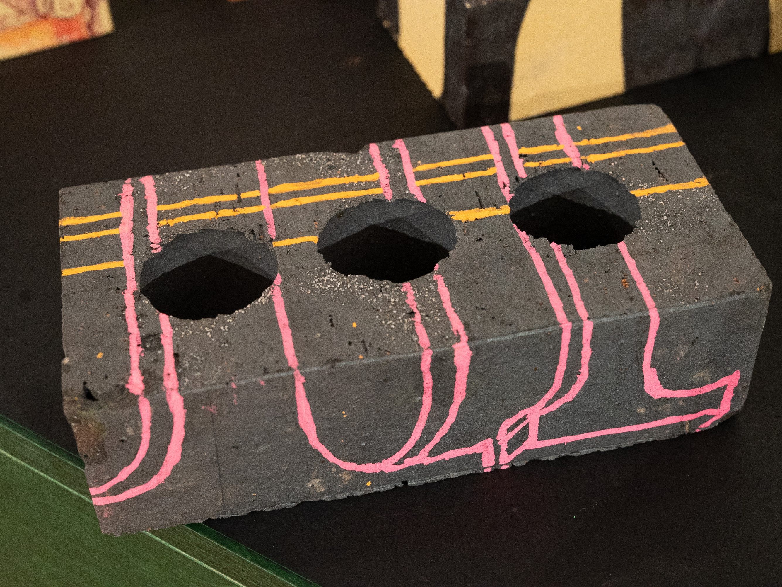 Brick painted black with pink and yellow painted lines