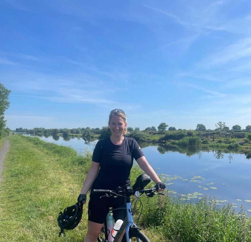 Emily Badger smiling on her bike next to a river on a sunny day