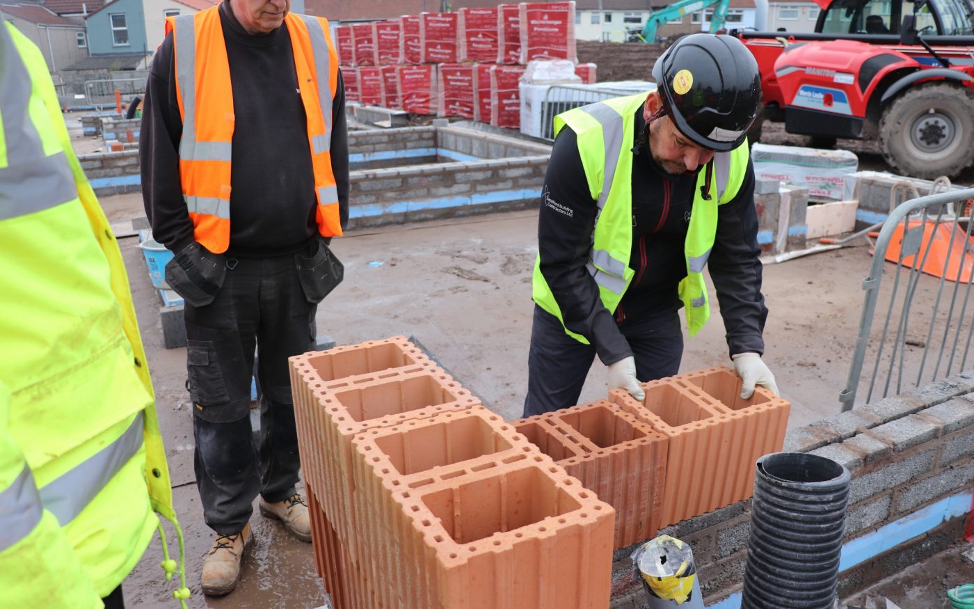 Men in safety gear laying Porotherm clay block walling
