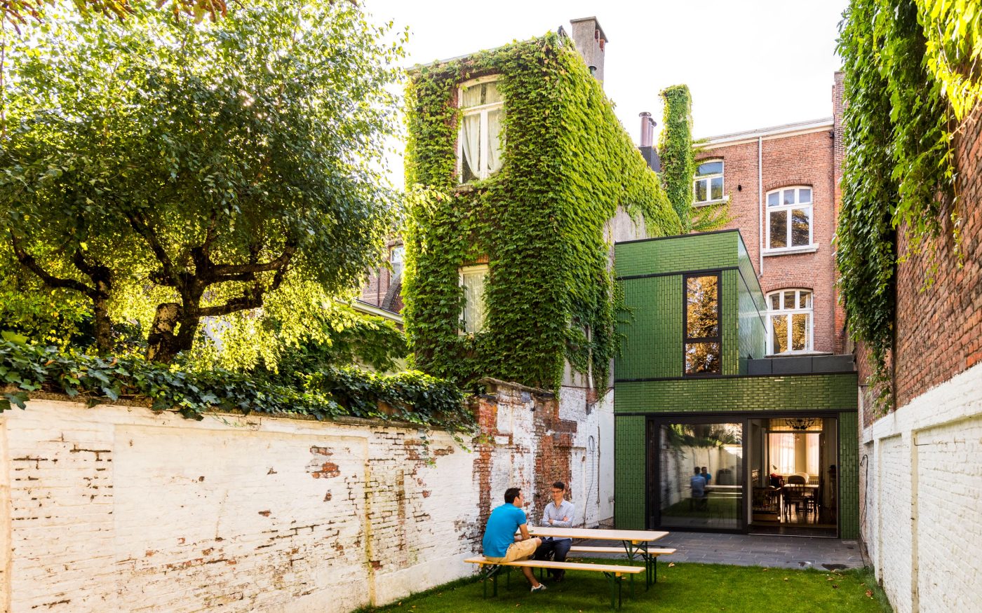 Man in garden of modern house with green glazed bricks