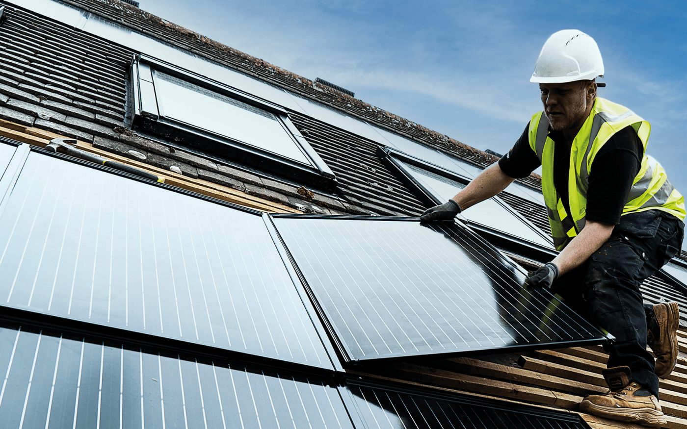Man on a roof installing in-solar roof panels