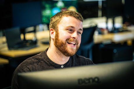 Man sat in the office smiling over his computer