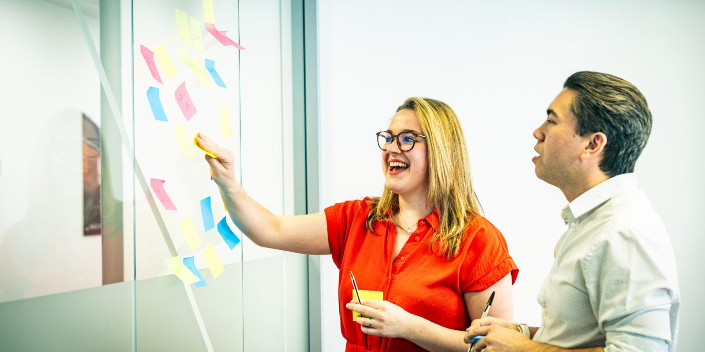 2 people in the cheadle office placing post it notes onto a glass wall