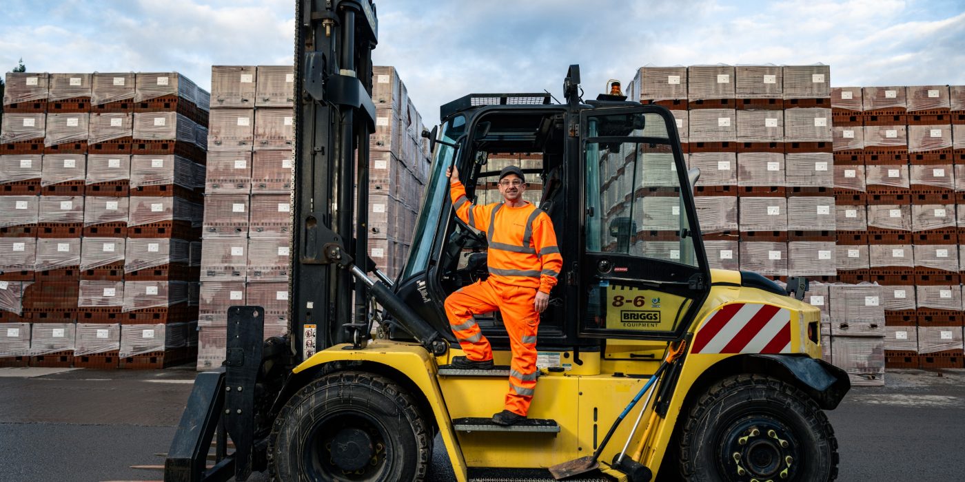 Man smiling stood on a fork lift at the denton factory