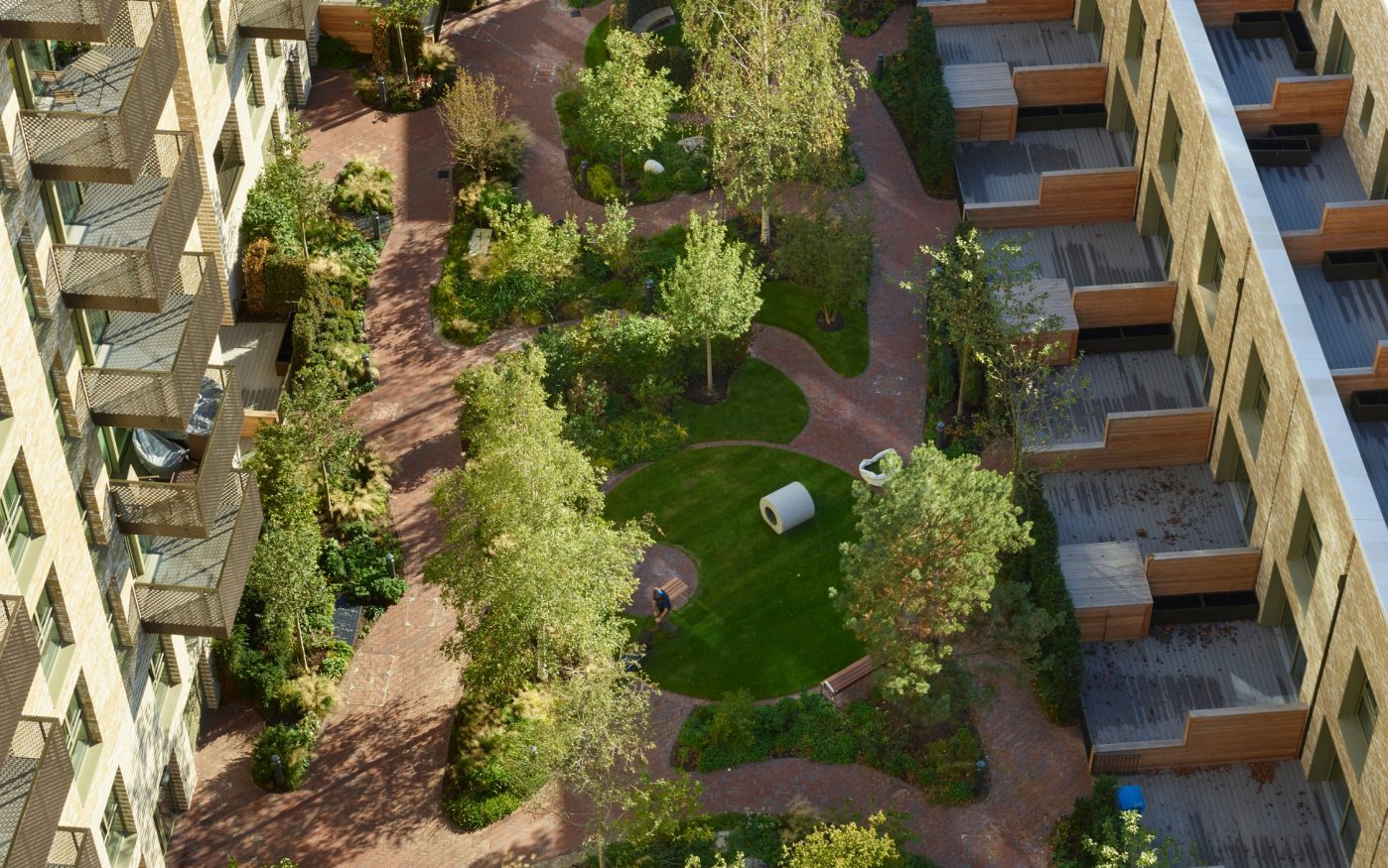 Aerial view of park with paved footpaths surrounded by apartment buildings