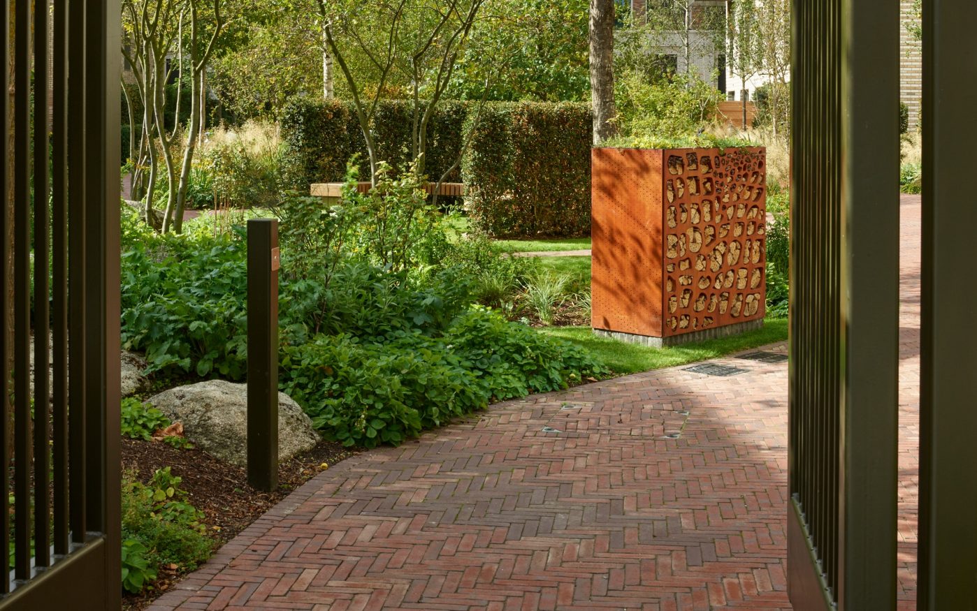 Open gate leading to paved path through green park