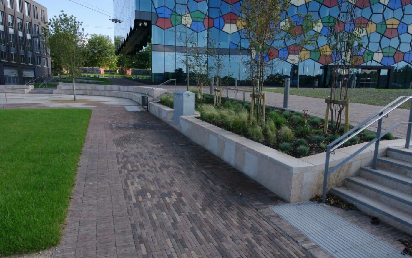 Clay paved path with stairs on right, building in front, and greenery on left