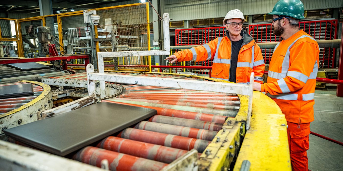 2 people in the factory in full PPC looking at something to their left