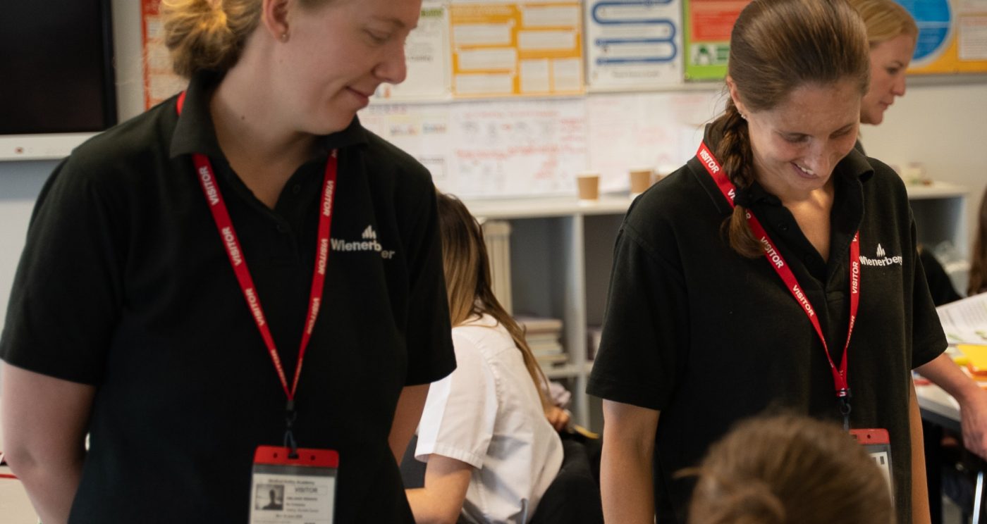 Two wienerberger employees smiling at primary school students