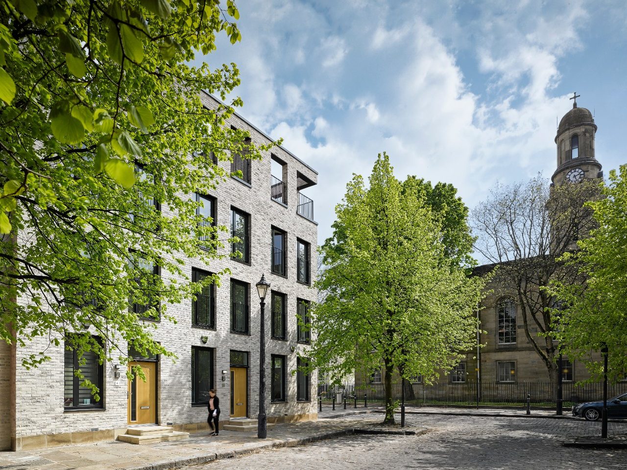 Green trees and modern grey brick terraced houses on sunny day