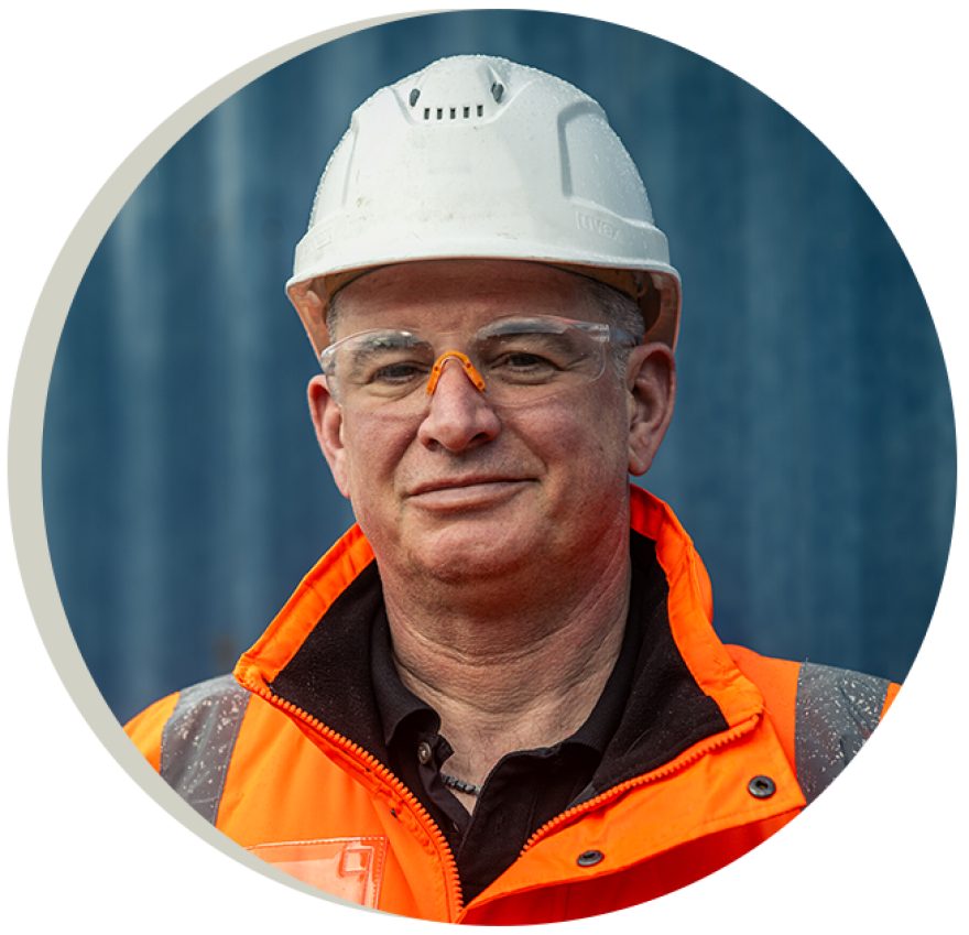 Portrait of Leigh Smith a stock yard manager in hi-vis jacket and white helmet