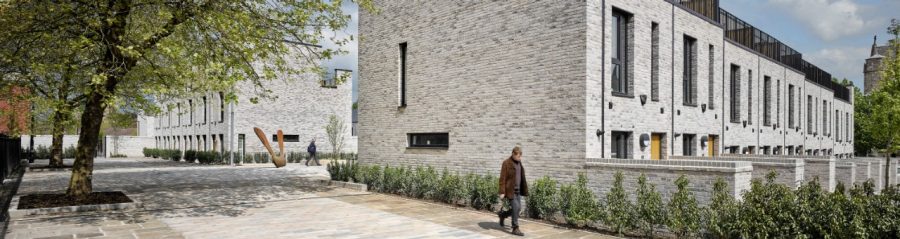 Man walking past modern brick terraced houses on sunny day