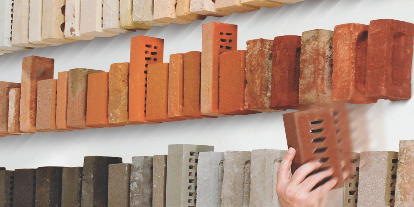 Hand reaching to place brick sample on shelf
