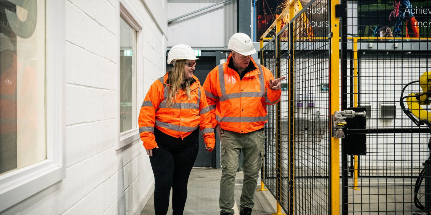 2 people in the factory in full PPC looking at something to their left