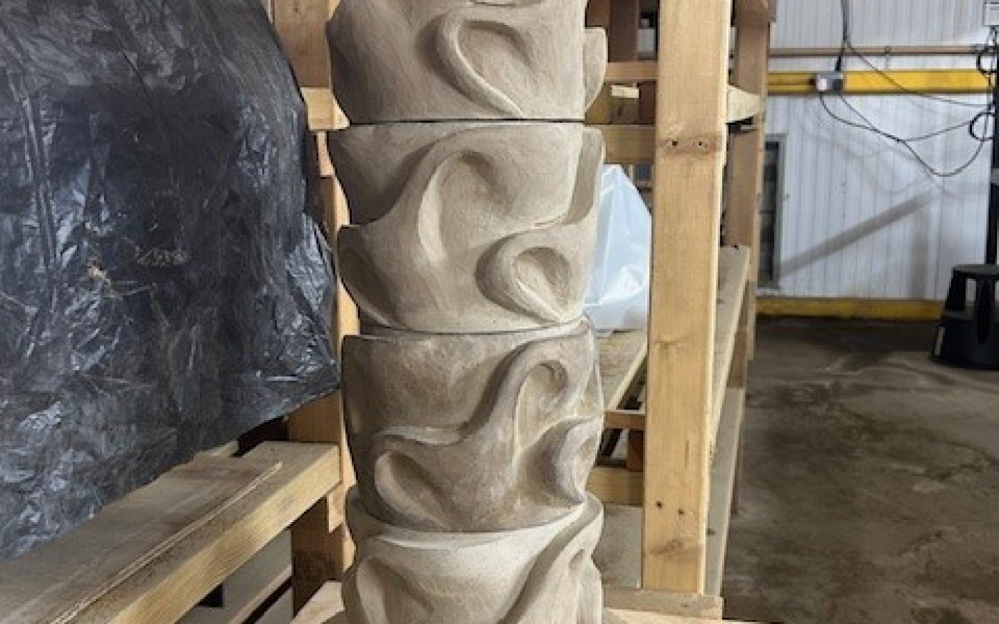 Tall clay sculpture with texture and swirls around the outside