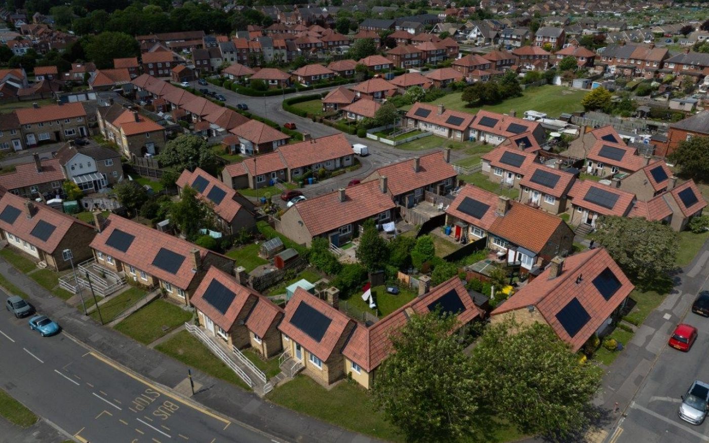 Top-down view of a housing estate with red tiled roofs fitted with dark grey solar panels