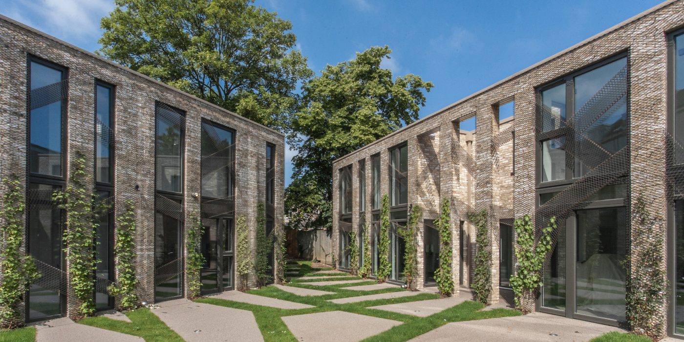Modern brick terraced houses with tall windows and climbing plants around a landscaped courtyard