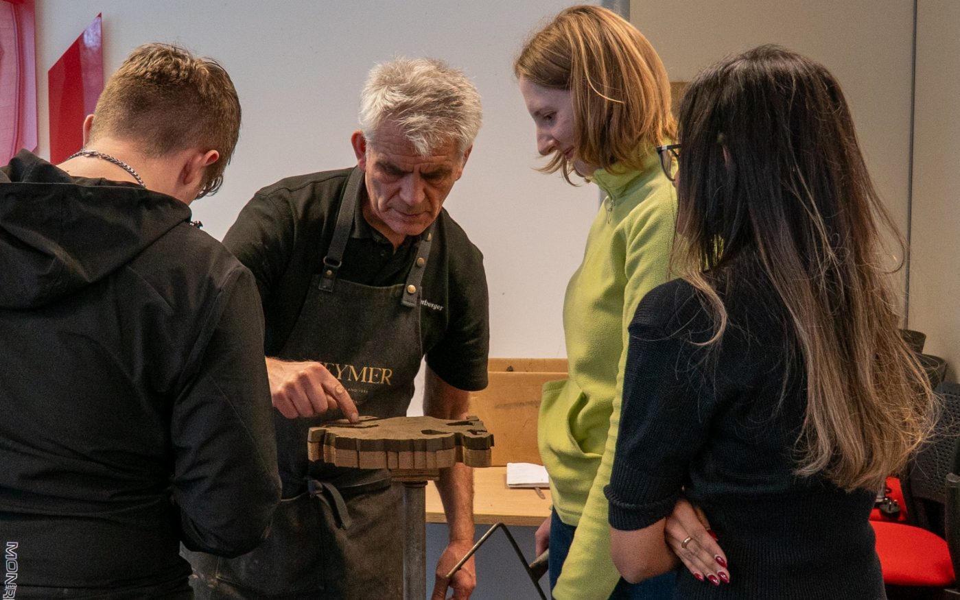 Young people watch Ian Martinson, carver of clay, work