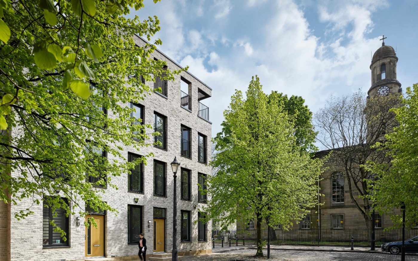 Timekeerpers Sqaure townhouses in Salford with historic church and green trees