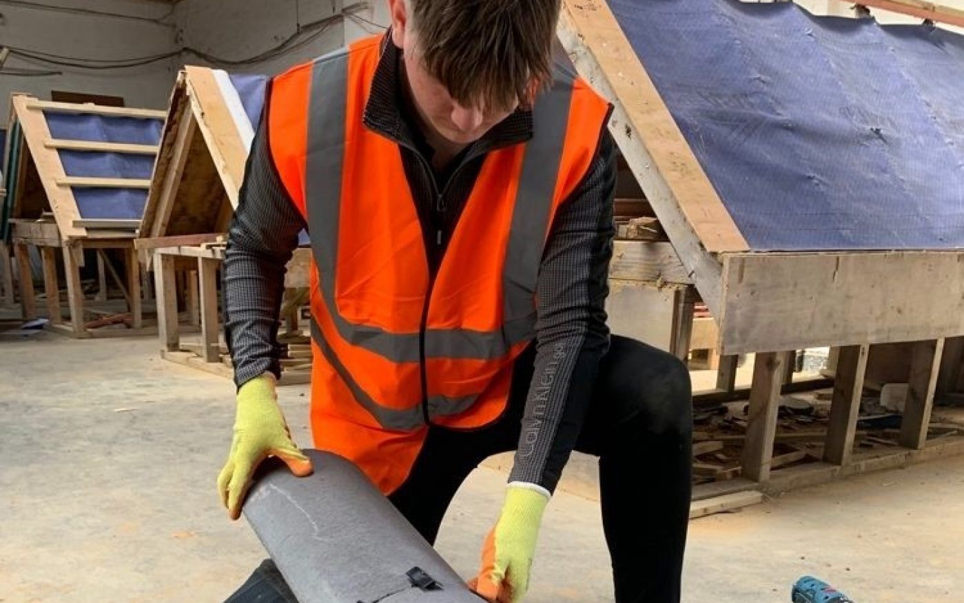 Young man knelt down adding a roof accessory to a demo roof