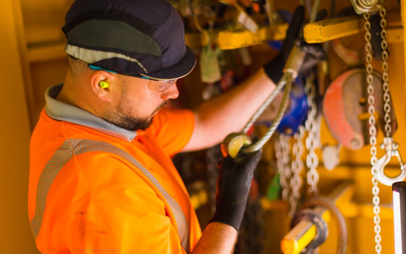 Man in hi vis inspecting a piece of machinery in the factory