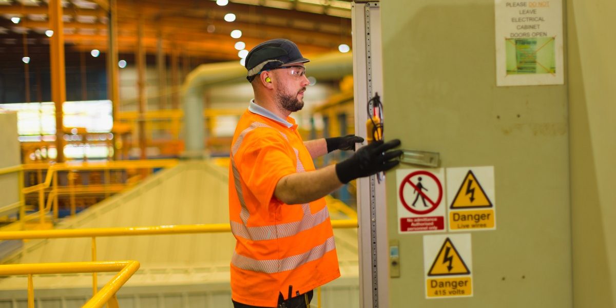Man working in factory looking at a piece of machinery