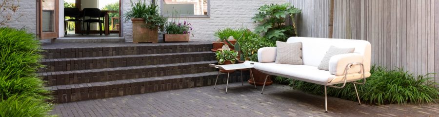 Clay paved modern garden with steps and sofa